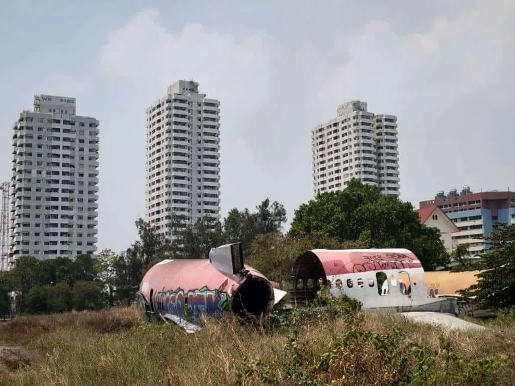 Rozbite fragmenty samolotu z graffiti w trawie, w tle wysokie bloki mieszkalne