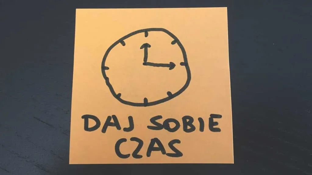 Pomarańczowa karteczka z narysowanym zegarem i napisem Daj sobie czas